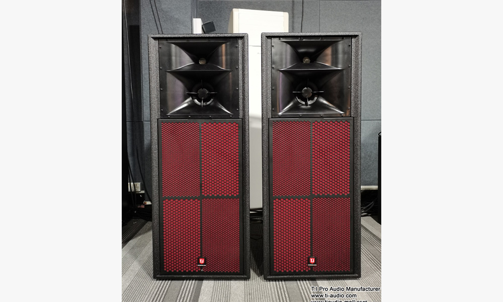 Two large black speaker cabinets with red grilles.  The speakers are set up side-by-side on a tiled floor.