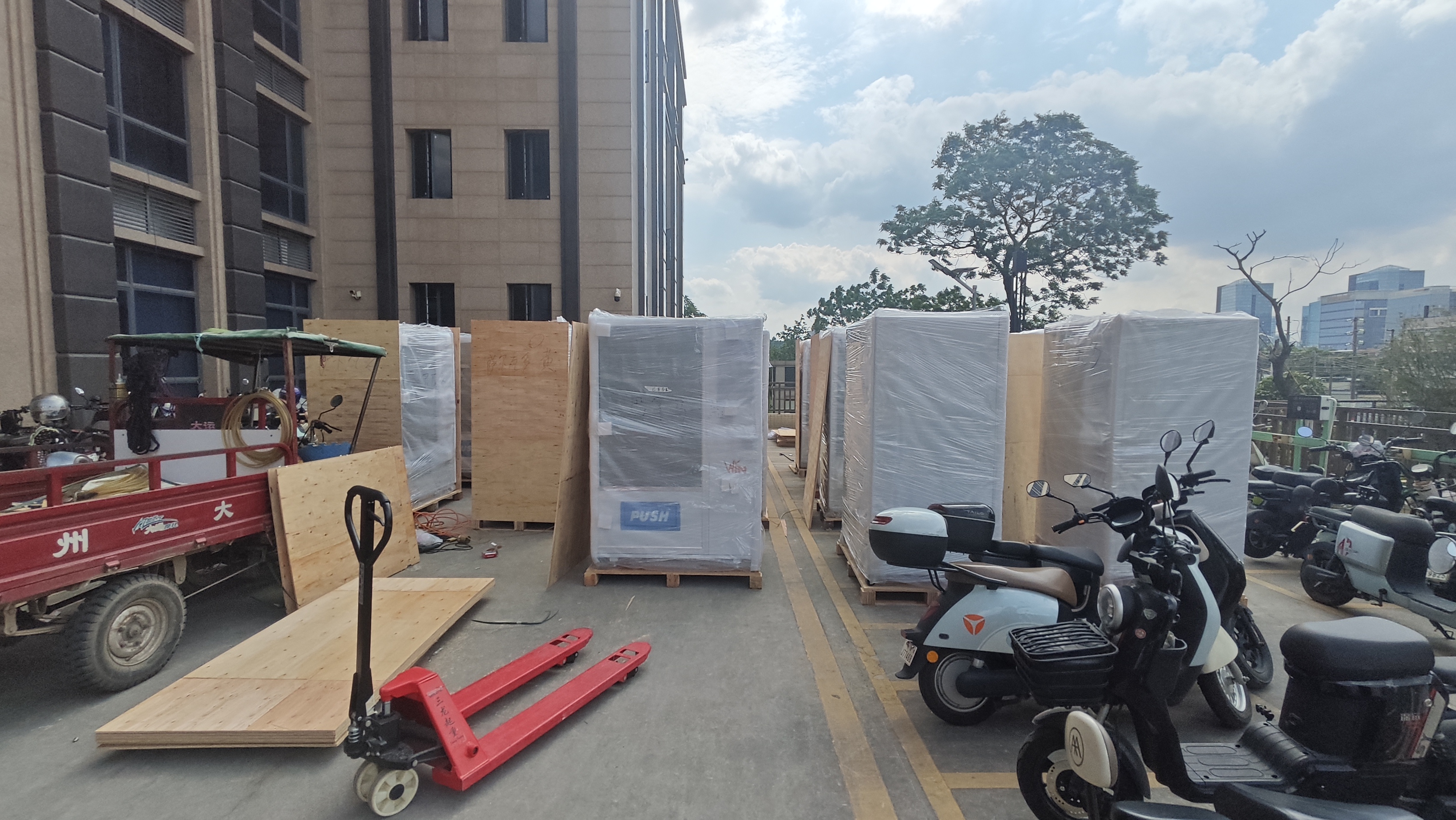 Vending machines are being packed into wooden crates outside a building for shipping.
