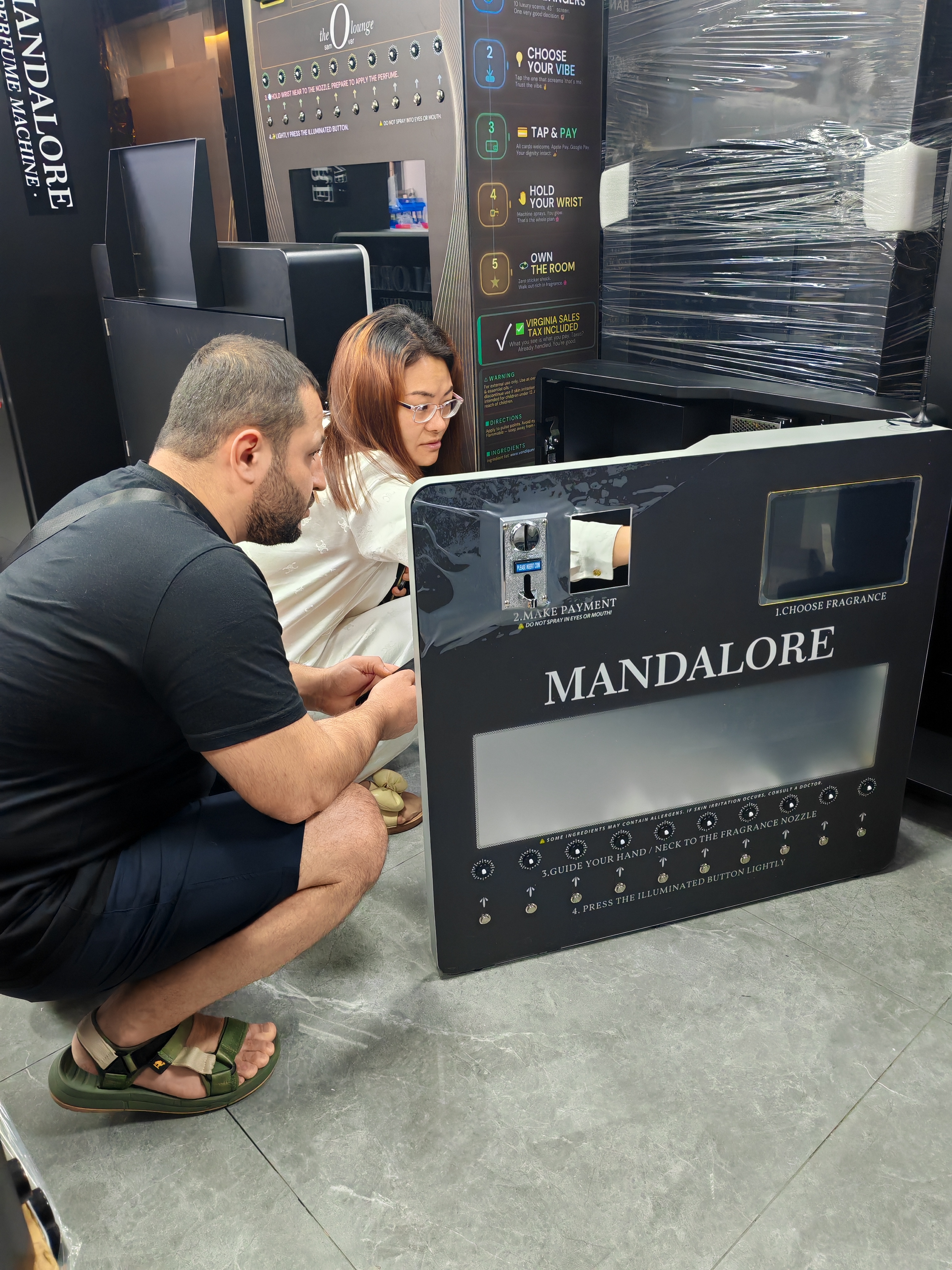 A Tajik customer learns about the inside of the MAKMIK perfume vending machine.