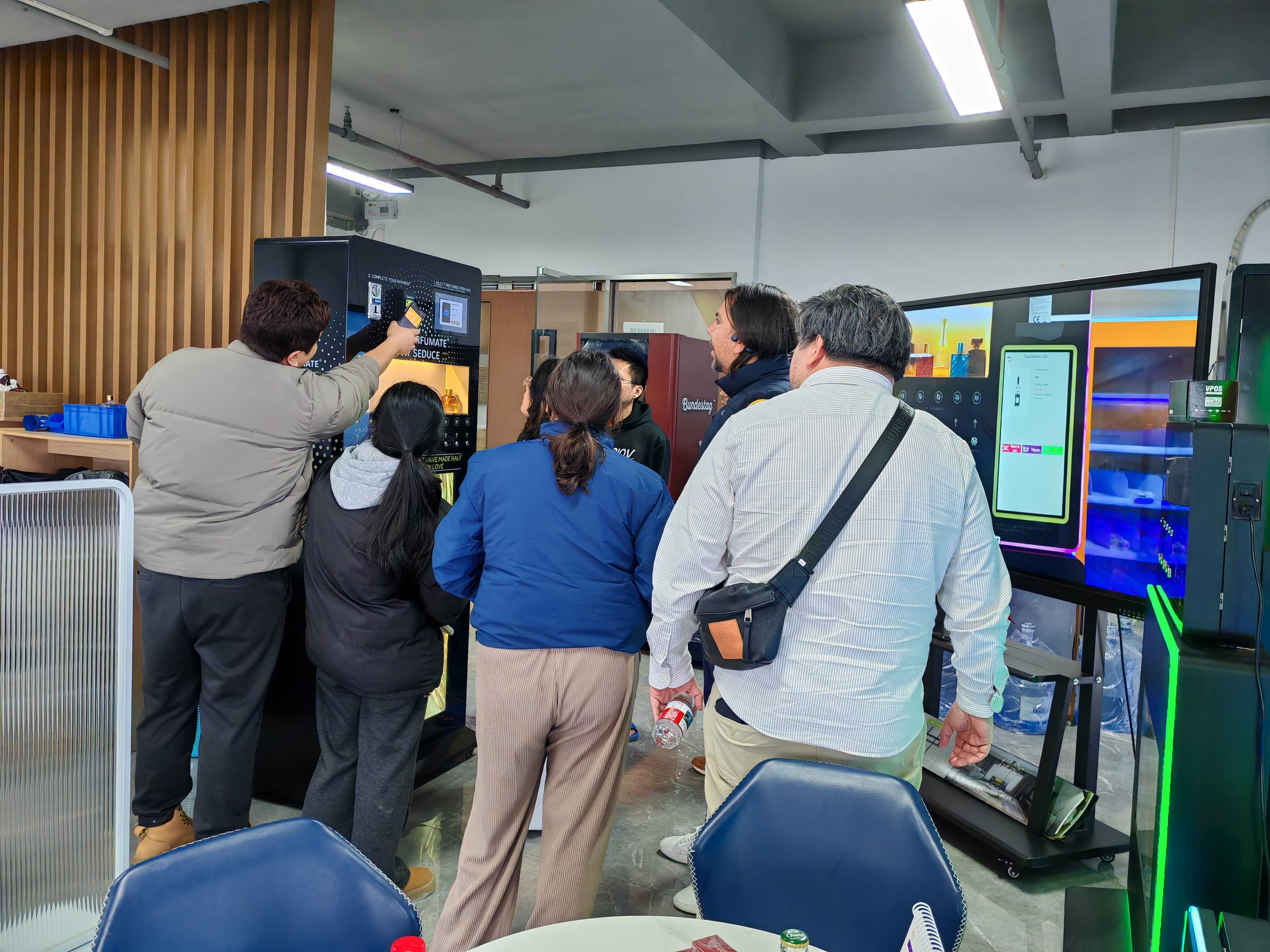 People testing the customer experience perfume vending machine with digital displays.