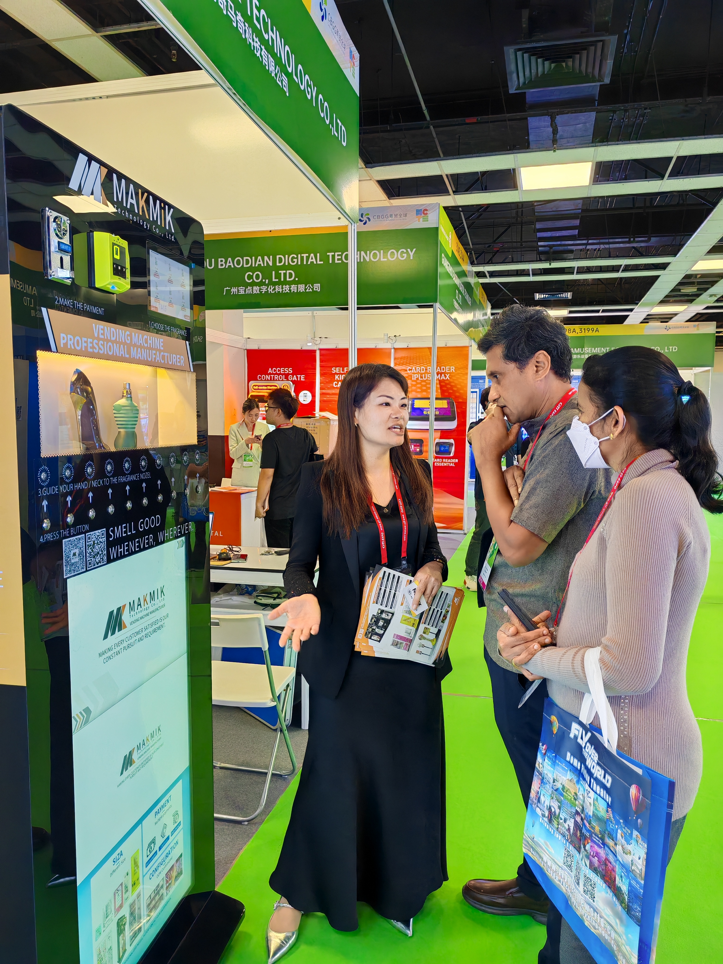 Lors d'un salon professionnel, des employés de MAKMIK présentent le distributeur automatique de parfums aux clients. Ces derniers écoutent attentivement.