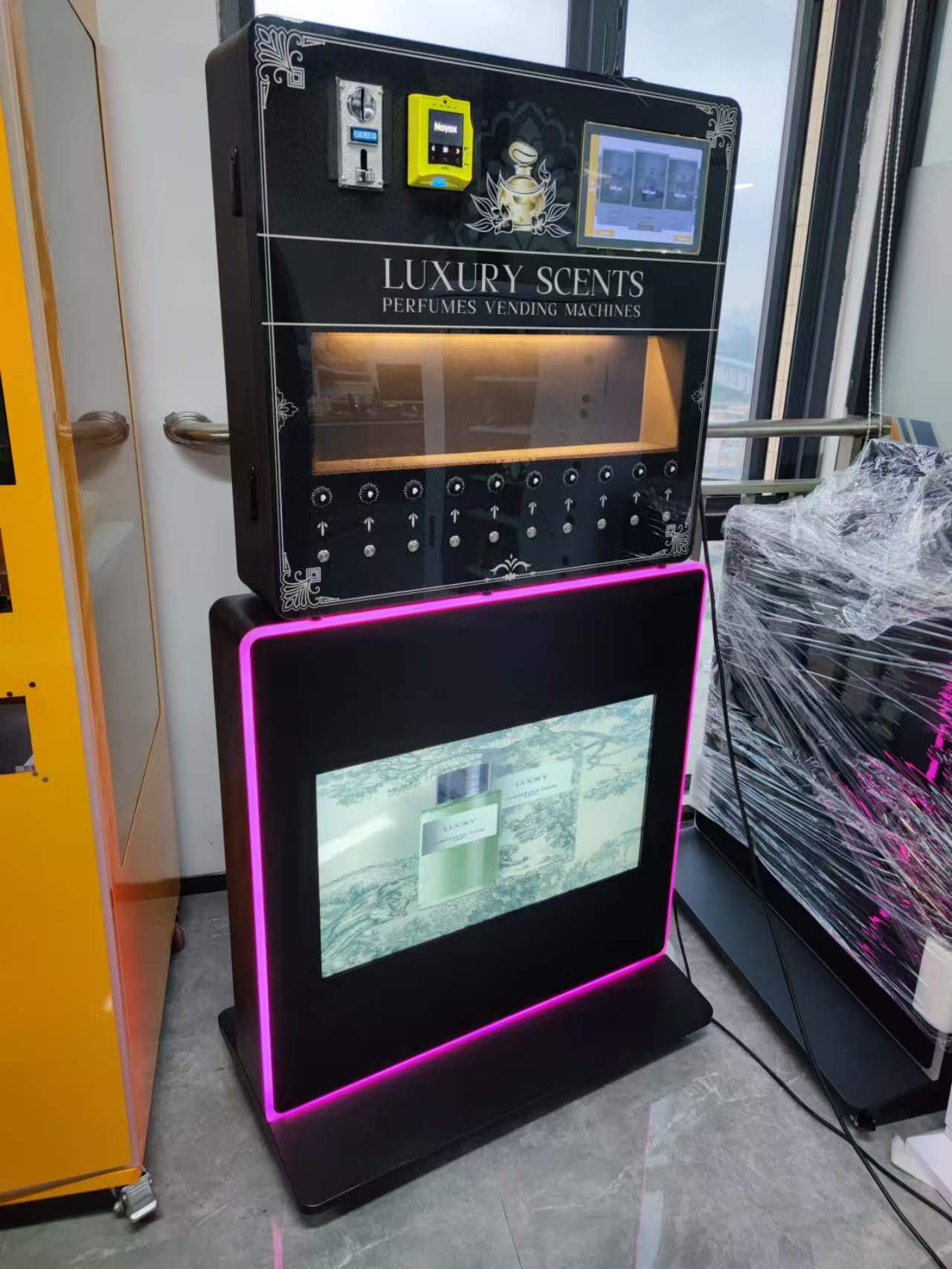 Display of a small wall-mounted MAKMIK perfume vending machine with 10 spray nozzles and a stand.