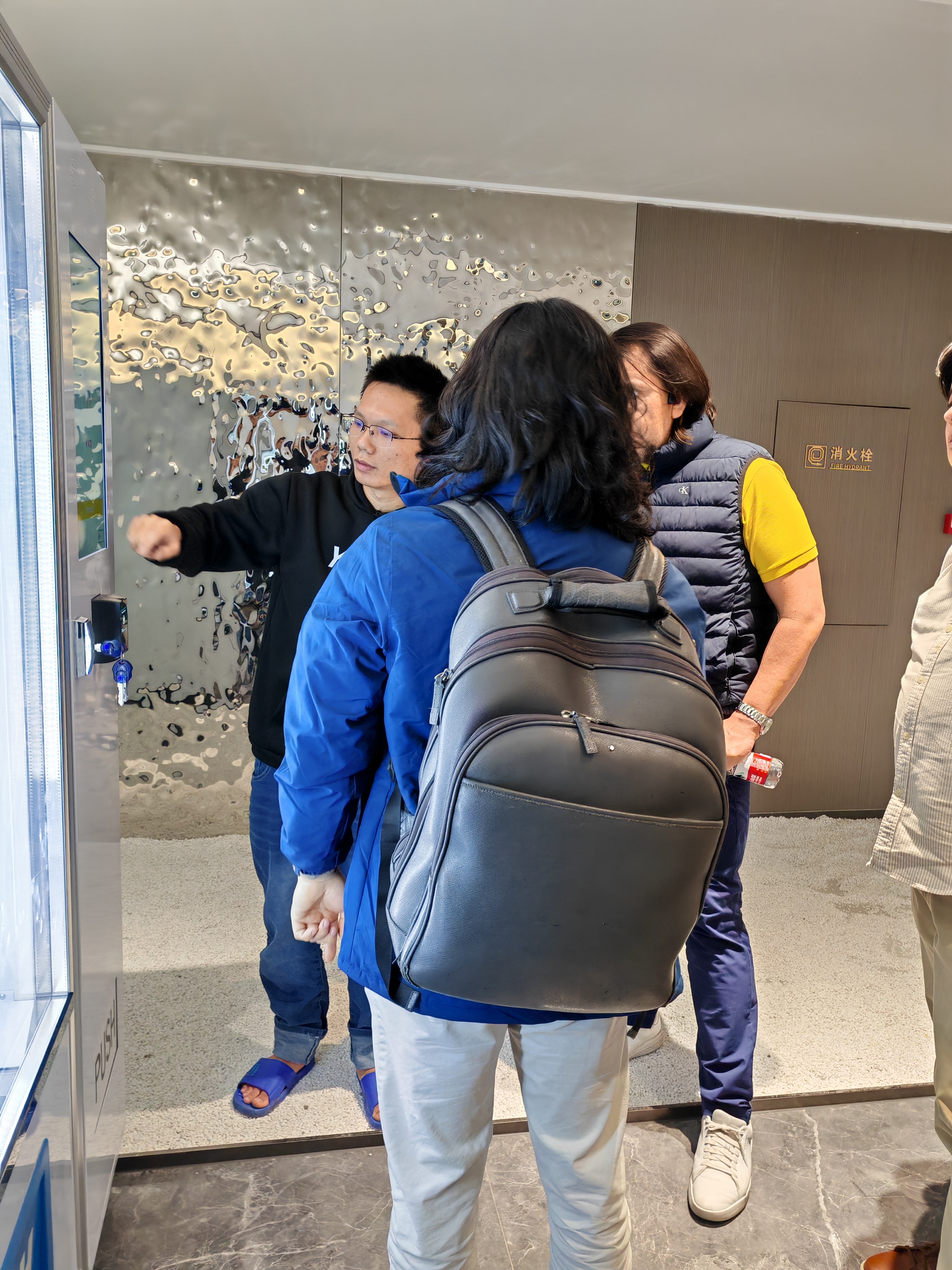 The customer observes the operation process of the vending machine while a staff member explains.