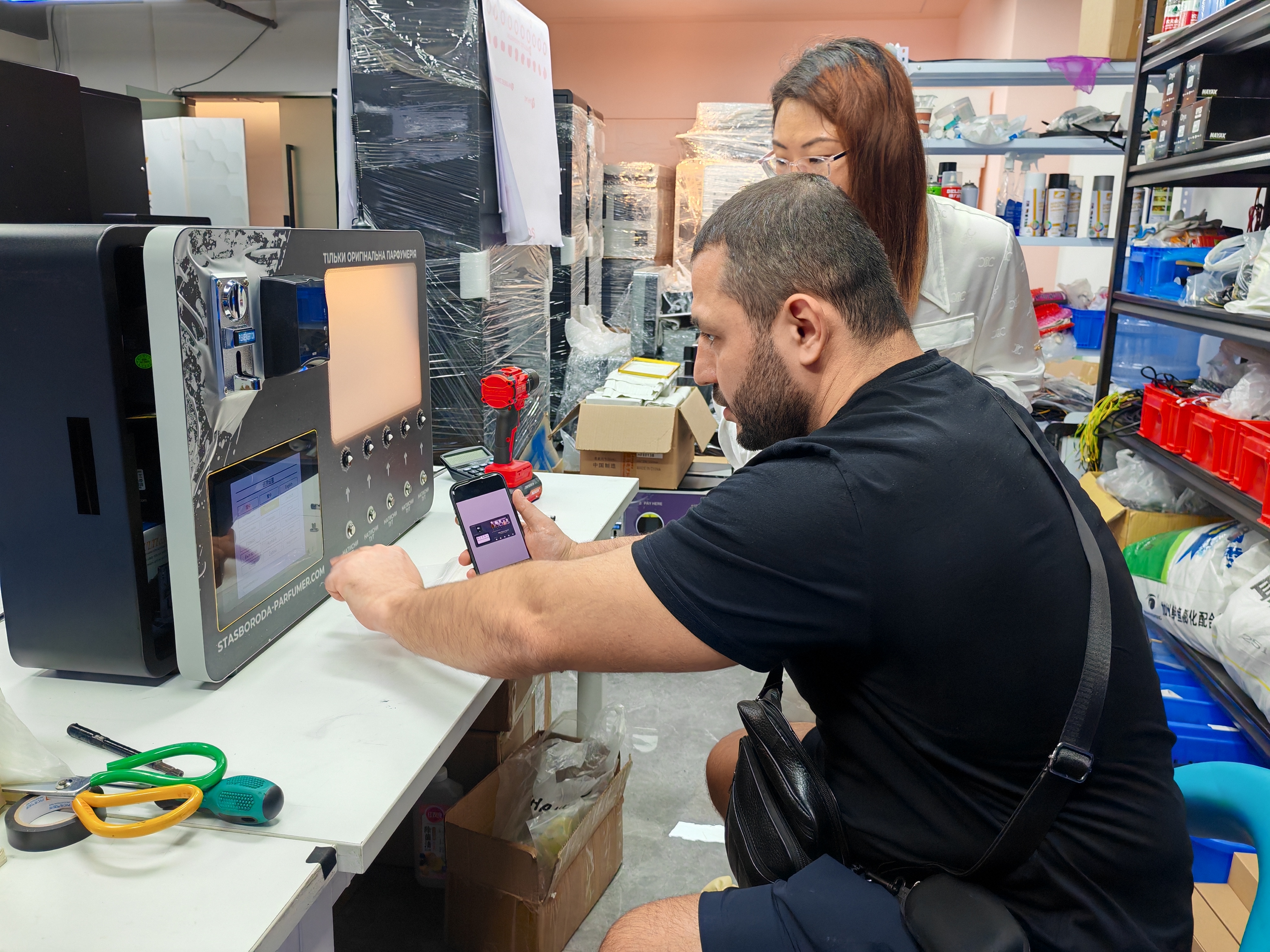 MK salesman GUGU introduces the wall-mounted, small, five-nozzle MAKMIK perfume vending machine to a customer in Tajikistan.