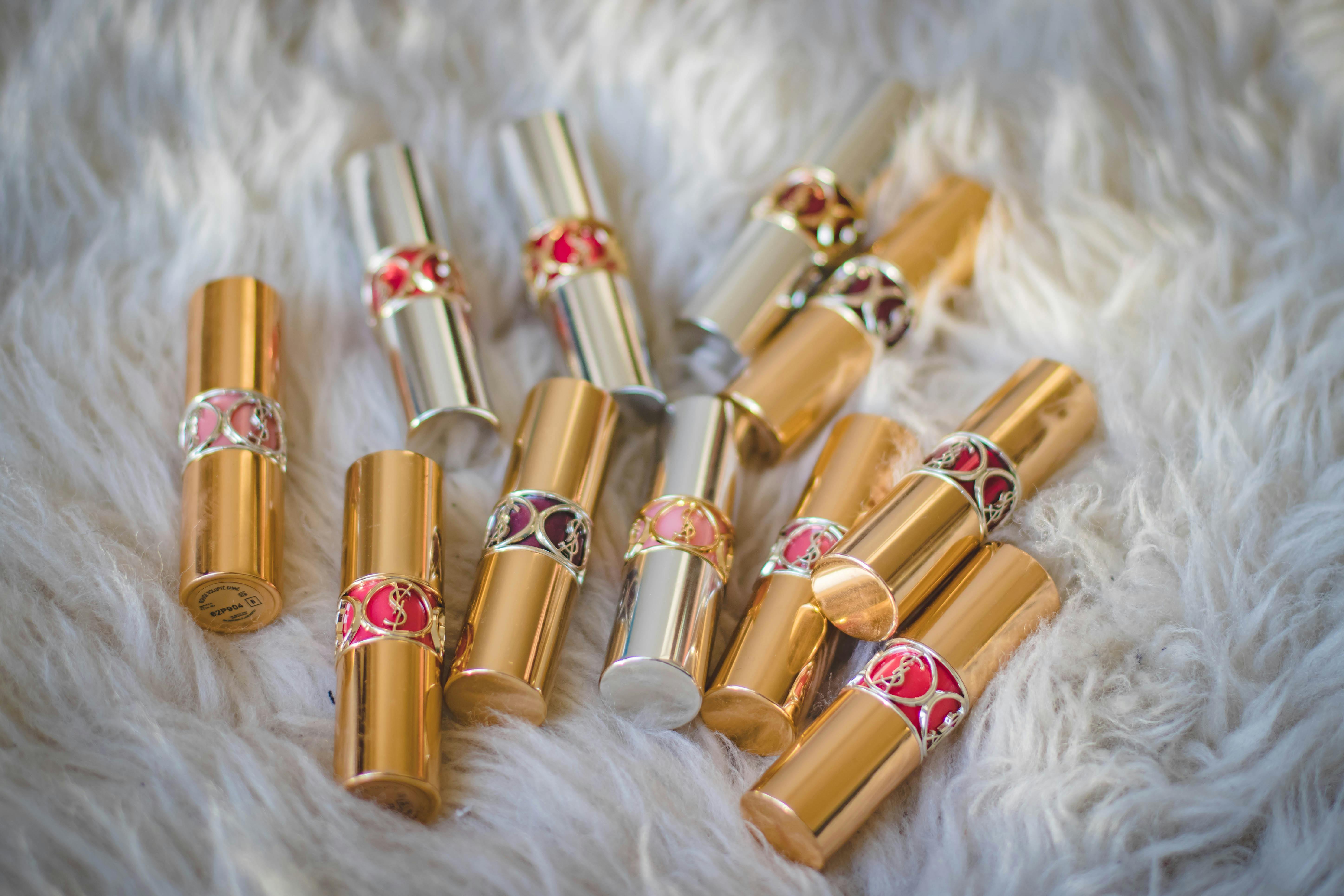 A collection of gold and silver lipstick tubes displayed on a fluffy white fur surface. A collection of gold and silver lipstick tubes displayed on a fluffy white fur surface.