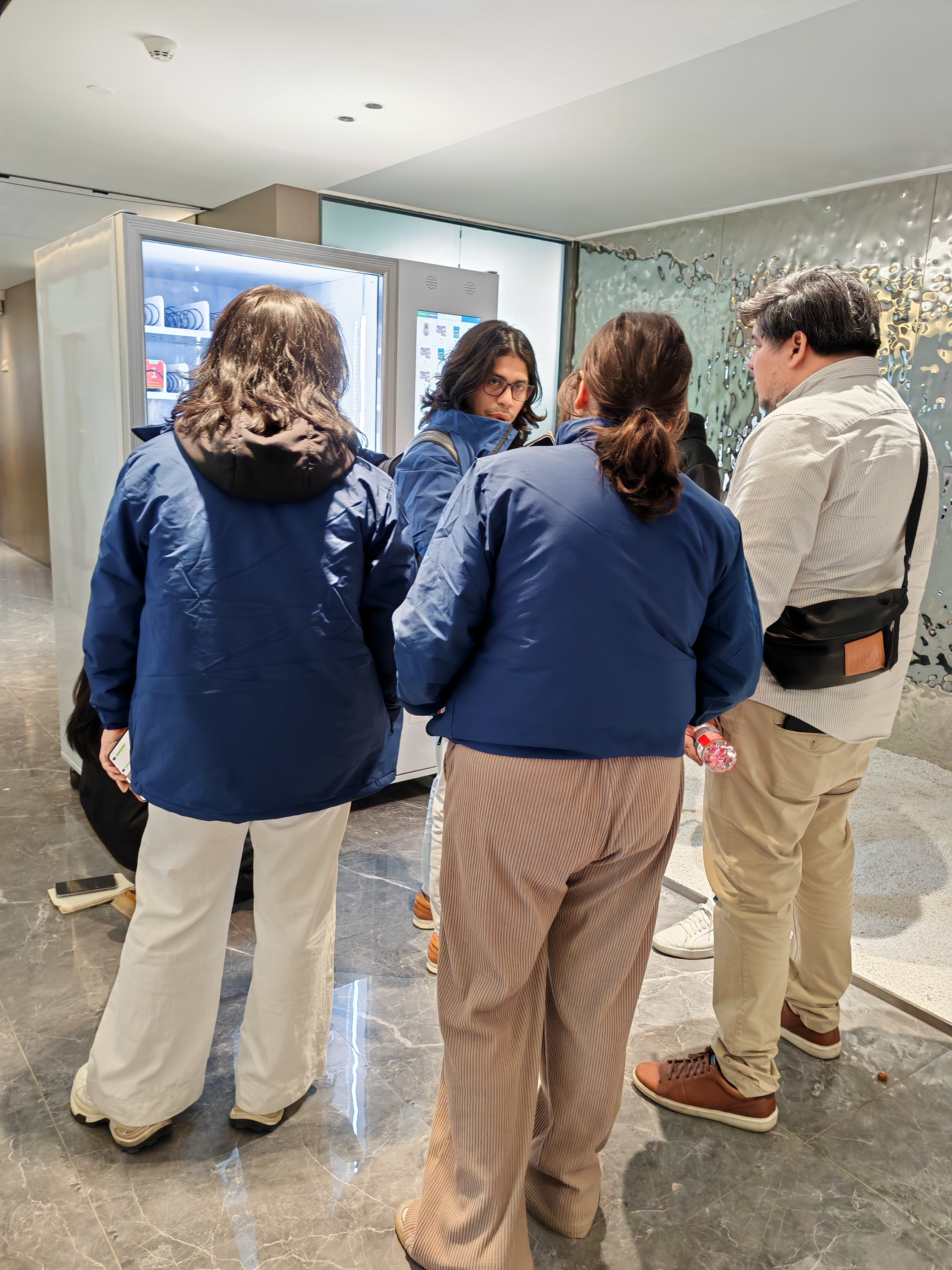 Customer evaluation of the vending machine meeting as a group gathers to inspect the digital display.