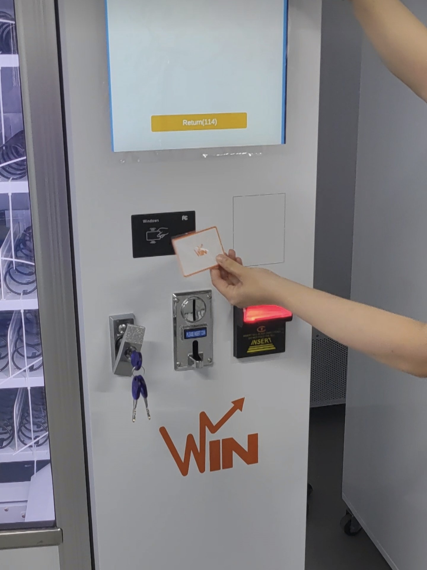 MAKMIK workers test the IC card function of the vending machine by tapping a card on the reader.