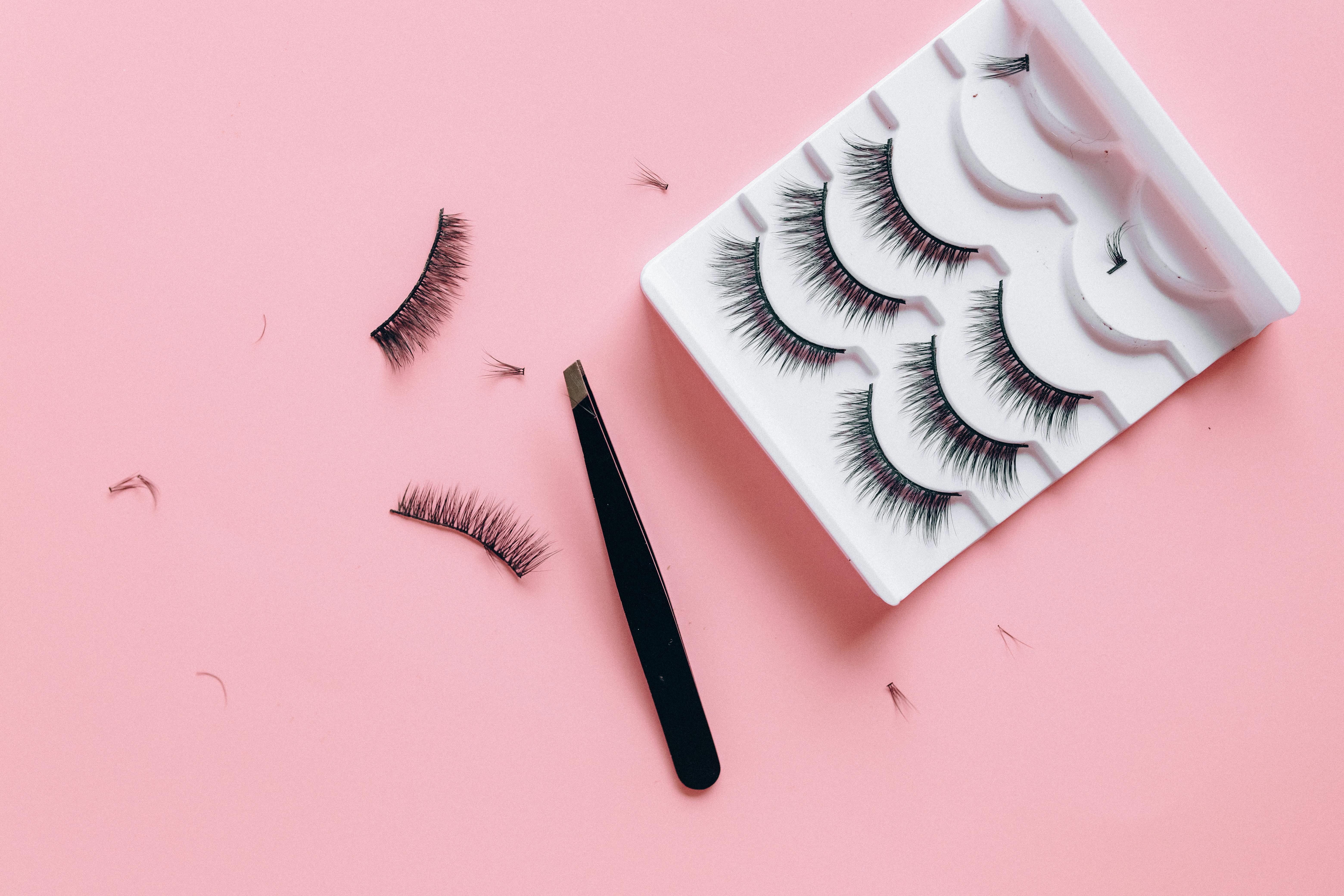 Stylish arrangement of false eyelashes and tweezers on a pink background, perfect for beauty themes. Stylish arrangement of false eyelashes and tweezers on a pink background, perfect for beauty themes.
