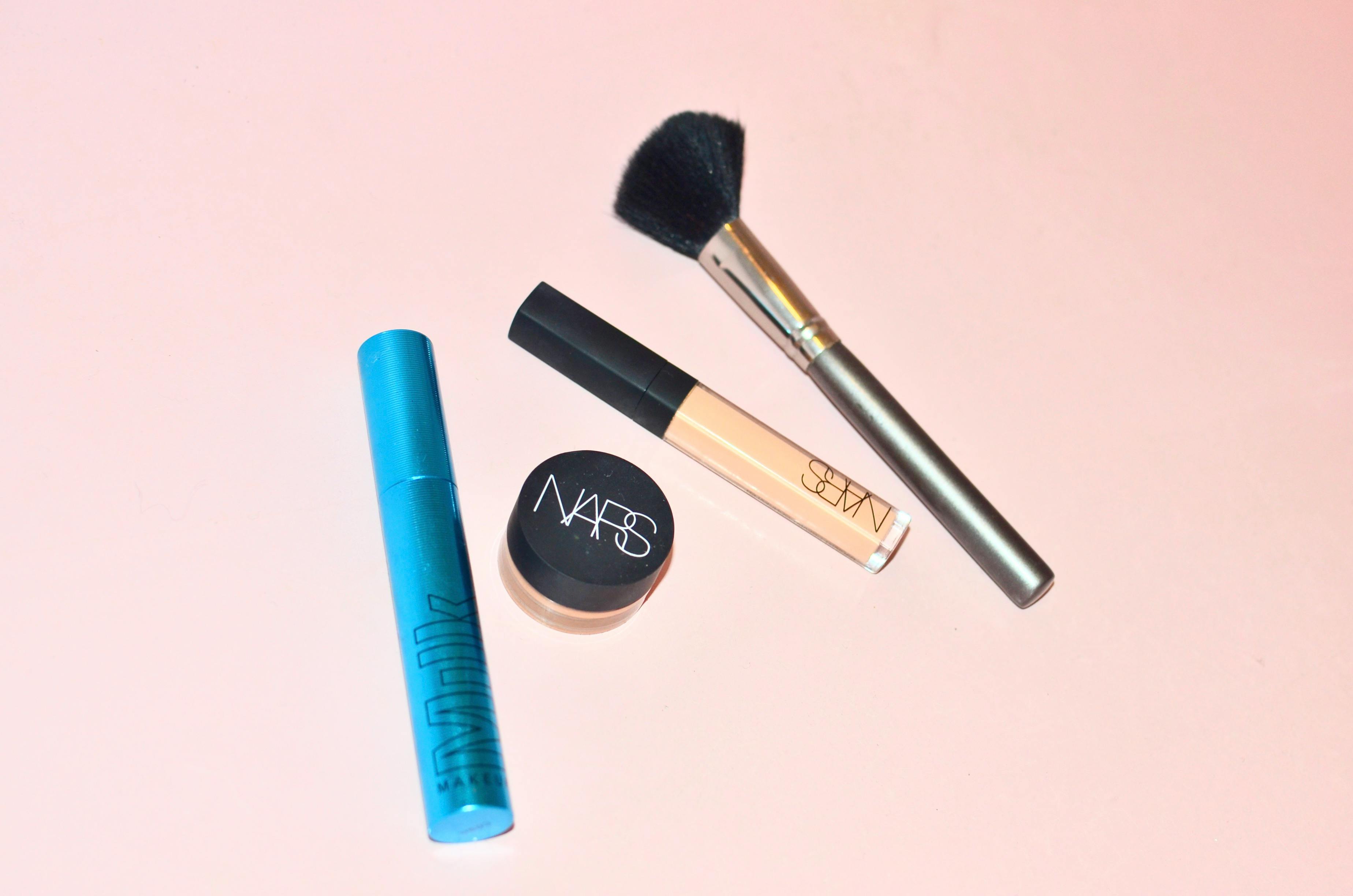 Top view of professional mascara concealer and cosmetic foundation placed near brush for applying makeup on pink background in studio Top view of professional mascara concealer and cosmetic foundation placed near brush for applying makeup on pink background in studio