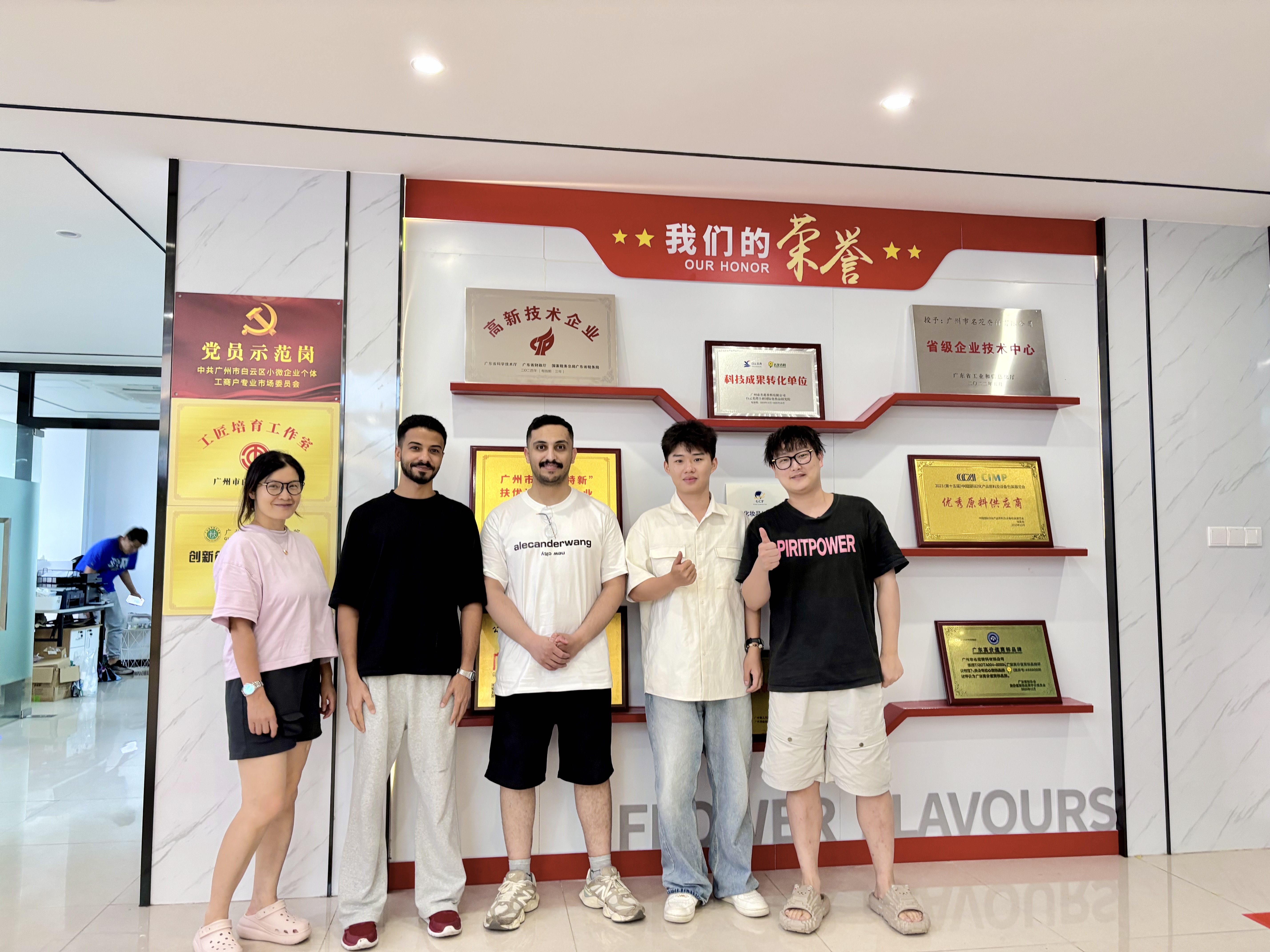 Group of people standing in front of a wall displaying company awards and honors.