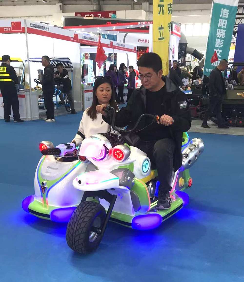 A couple riding together on an electric amusement motorcycle