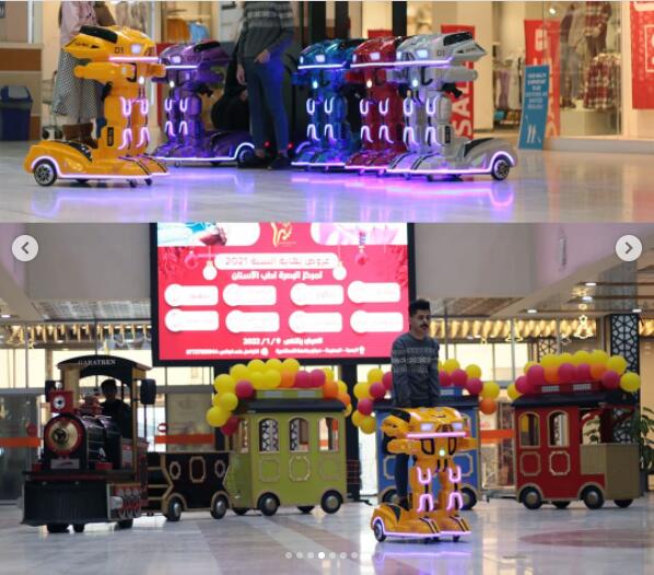 Boy riding a Kiddie Armored Robot Ride with a trackless train behind him