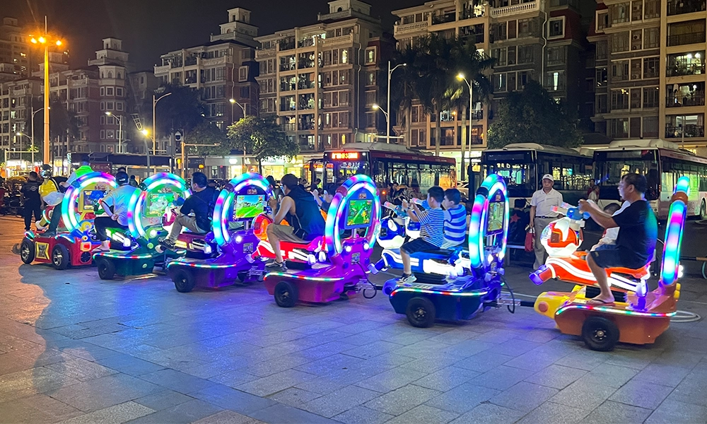 Children and adults riding illuminated nailong escort trackless train at night in a city square - H.Q.Amusement