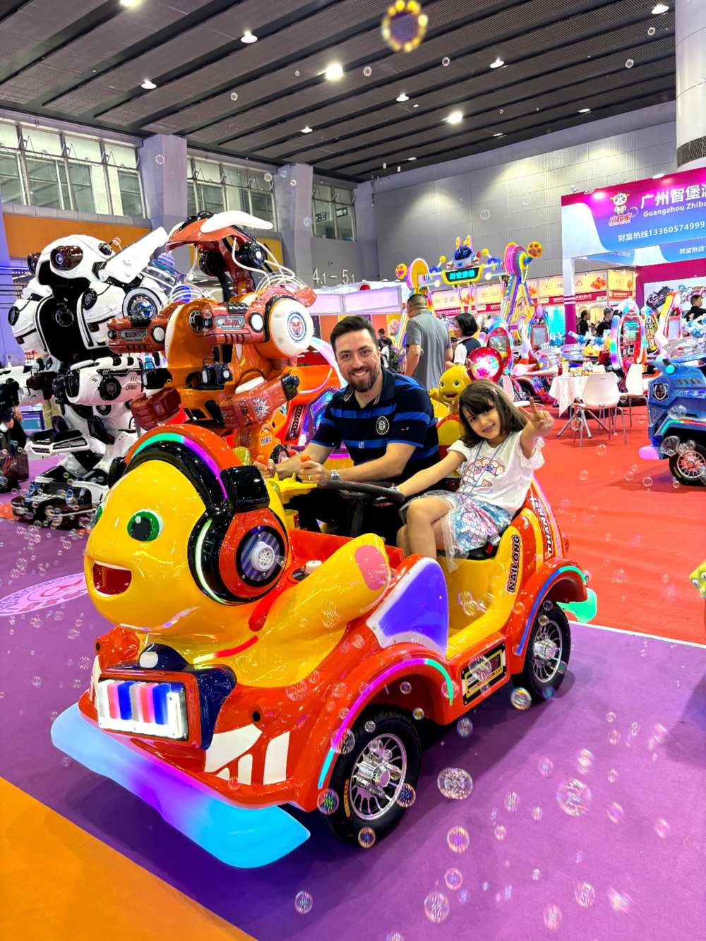 Father and daughter riding bubble-blowing nailong animal ride together
