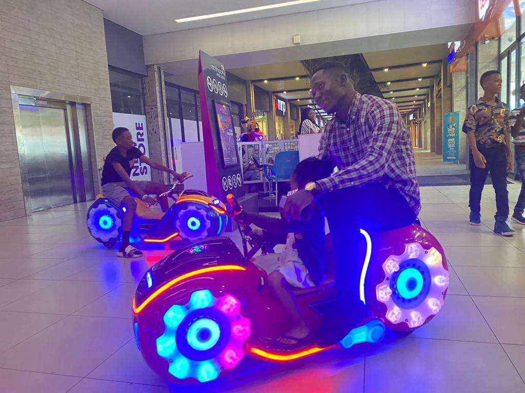 father and son riding amusement motorcycle together in Ghana