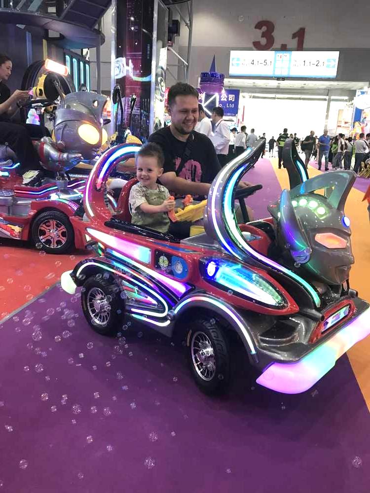 Father and son riding bubble-blowing Ultraman amusement car
