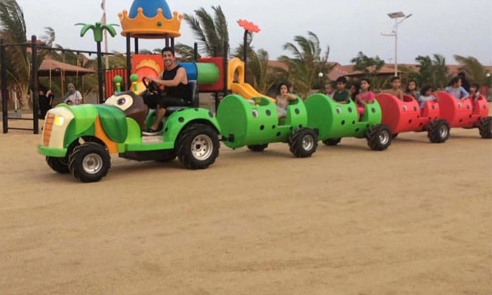 Man driving a ladybug caterpillar mini train ride with children on the Beach Playground - H.Q.Amusement