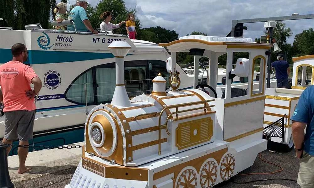 The decorative White Palace Train glides past while a Nichols boat sails in the background - H.Q.Amusement