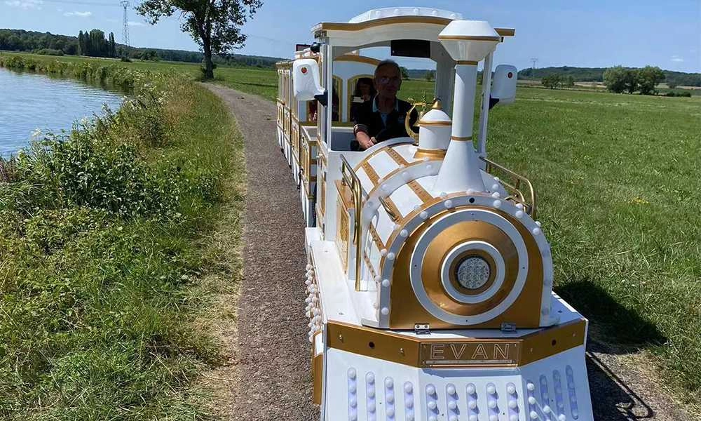 The elegant white-and-gold trackless train travels along a scenic canal path - H.Q.Amusement