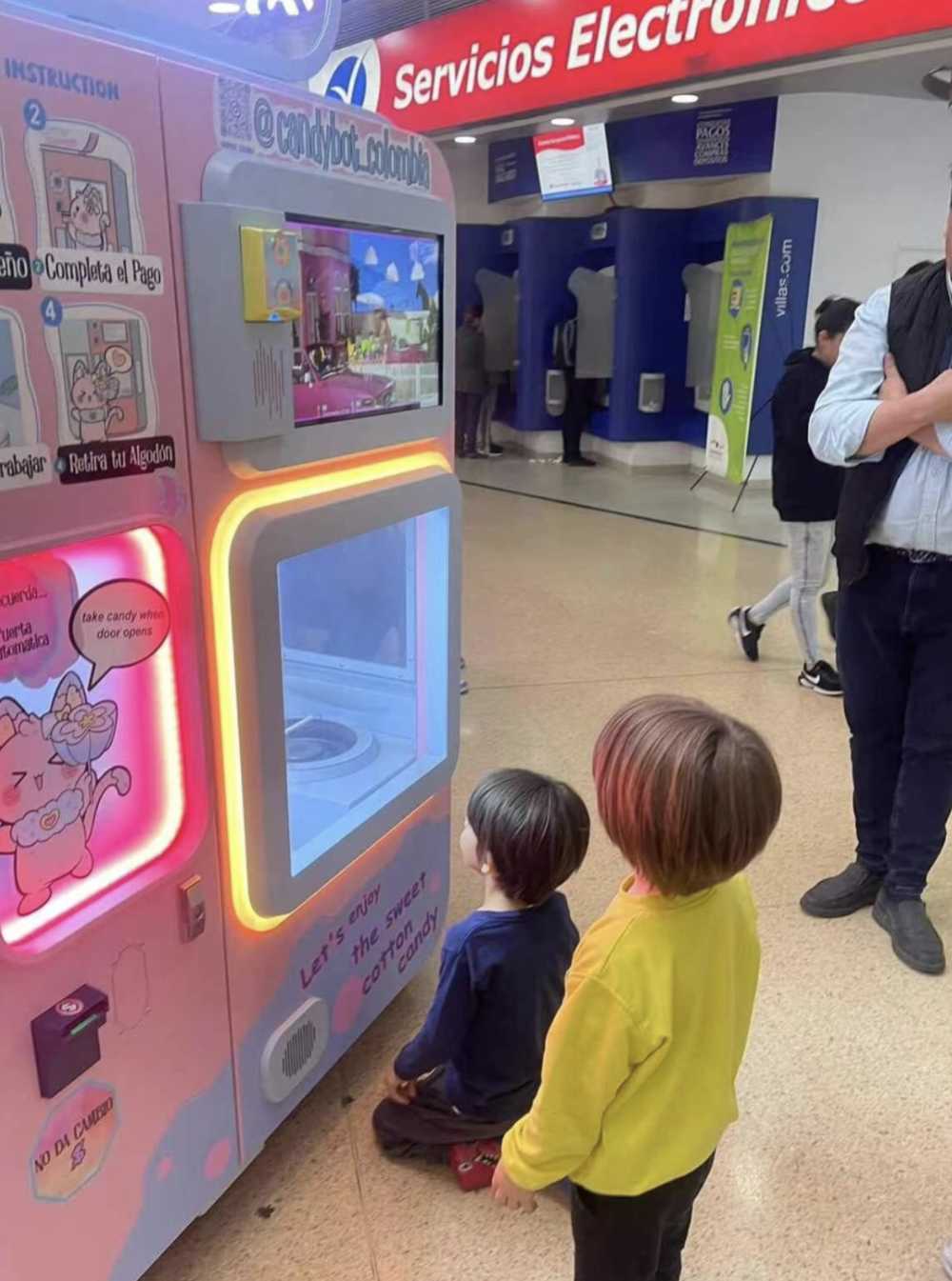 Two children waiting for their cotton candy in front of the automatic cotton candy machine