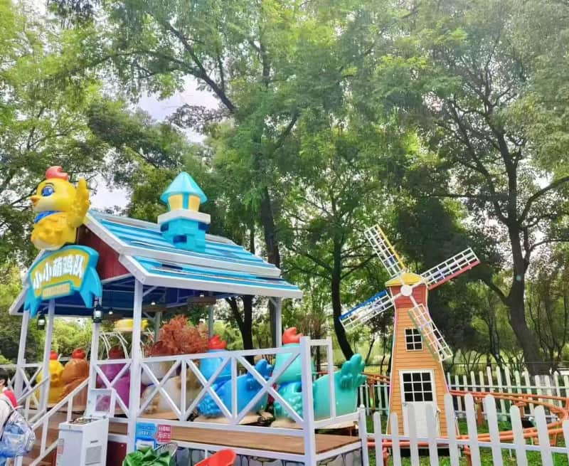 Manège coloré sur le thème des poulets dans un parc d'attractions extérieur au Brésil, avec moulin à vent et arbres. Mini montagnes russes à vendre, projet d'attraction familiale. - SUNHONG