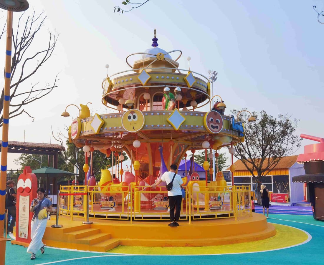 Tunggangan Larva Carousel dua peringkat berwarna-warni di taman hiburan.