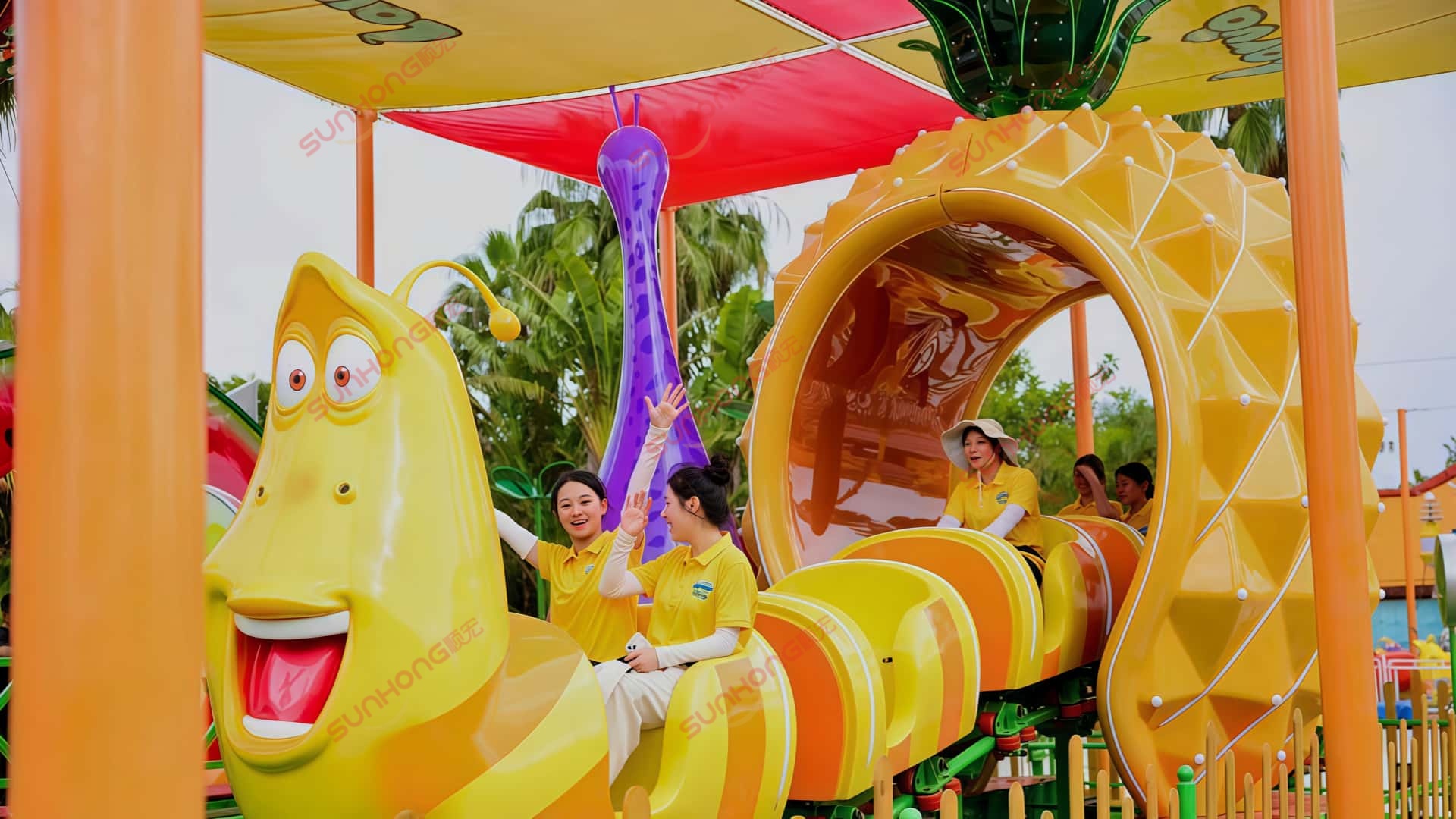 Excited Passengers Enjoying Larva Fruitland Mini Roller Coaster at Larva Adventure Theme Park Five female passengers laughing and enjoying the Larva Fruitland mini roller coaster ride, passing through a pineapple-shaped tunnel at Larva Adventure Theme Park in Seaside Bay. Theme park solutions providing thrilling experiences.