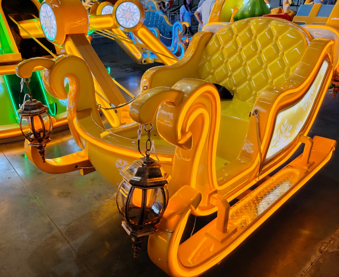 A bright yellow amusement park sleigh ride decorated with glowing lights and lantern-style ornaments. - SUNHONG