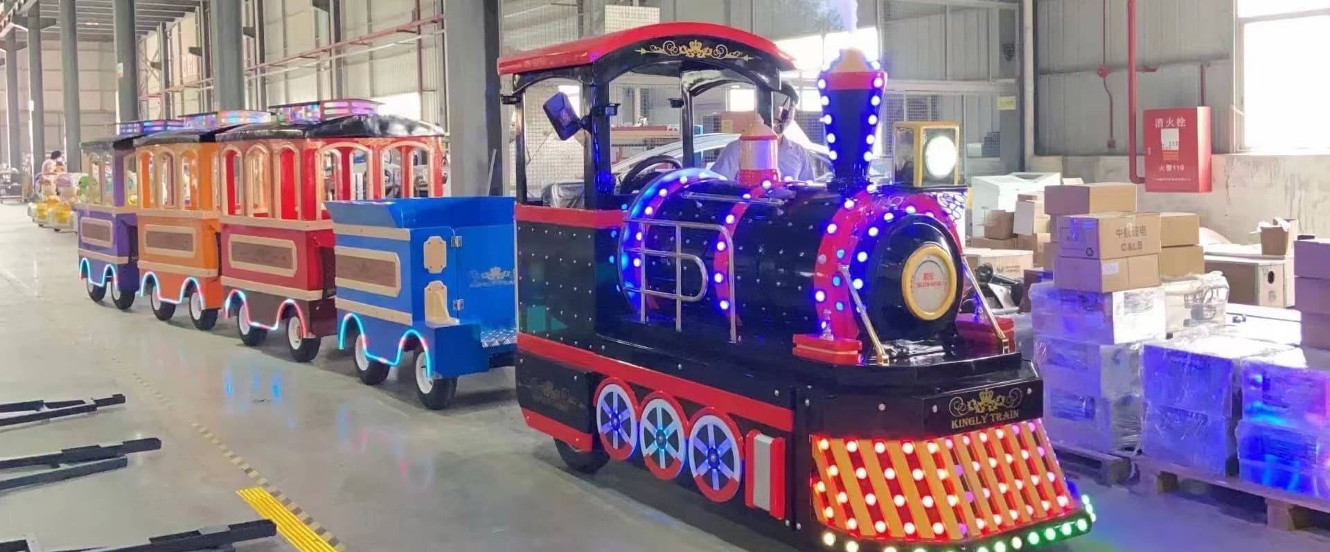 A colorful amusement park train ride with LED lighting displayed in a warehouse, designed for theme park transportation and amusement train ride attraction use