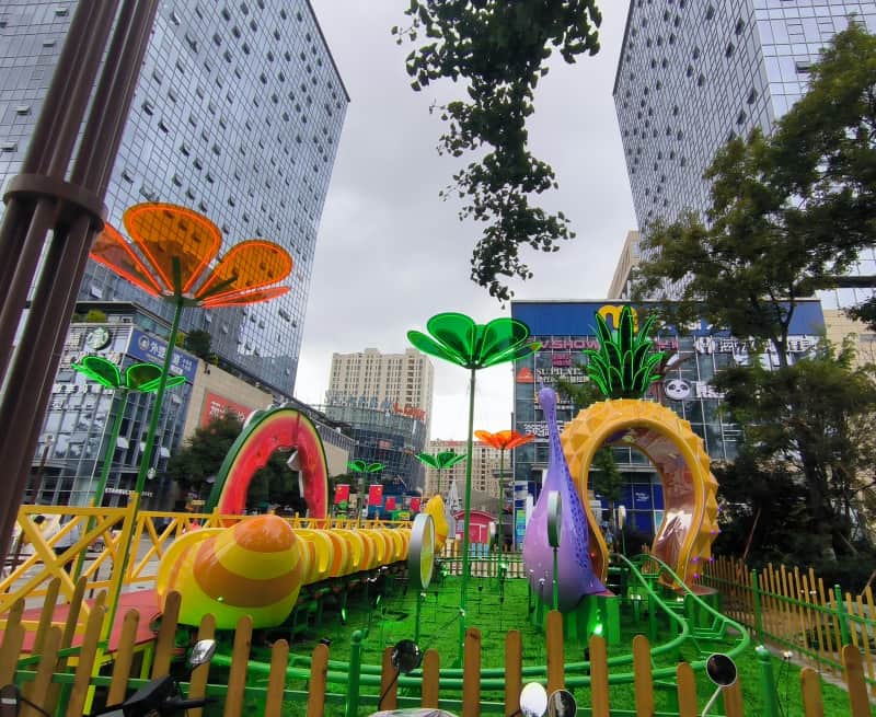 Aire de jeux et sculptures colorées sur le thème des fruits dans un parc urbain malaisien entouré de gratte-ciel. Mini-montagnes russes à vendre dans le cadre d'un projet de parc d'attractions urbain. - SUNHONG