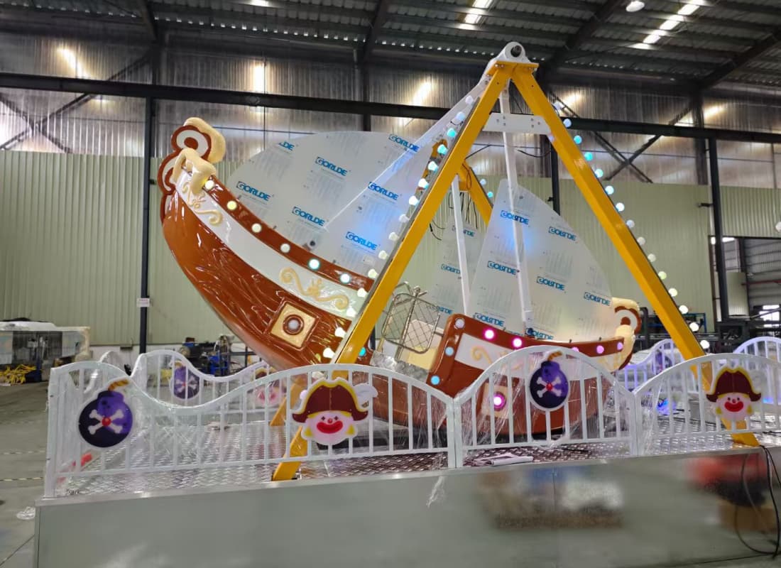 Vista nocturna del paseo en barco pirata oscilante con iluminación LED en temática de hielo.
