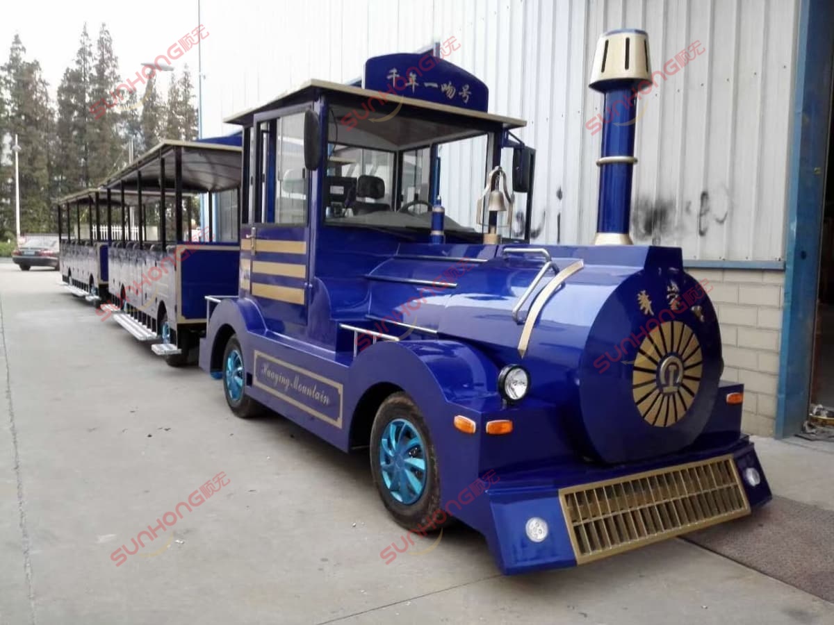 parque de atracciones-tren-azul-oro-fábrica Paseo en tren de diversiones con temática azul y dorada estacionado afuera de un almacén