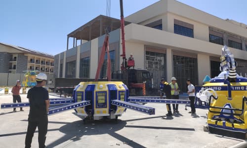 Instalação do brinquedo Time Jump em um parque de diversões, com operários orientando o processo de içamento e montagem. - SUNHONG