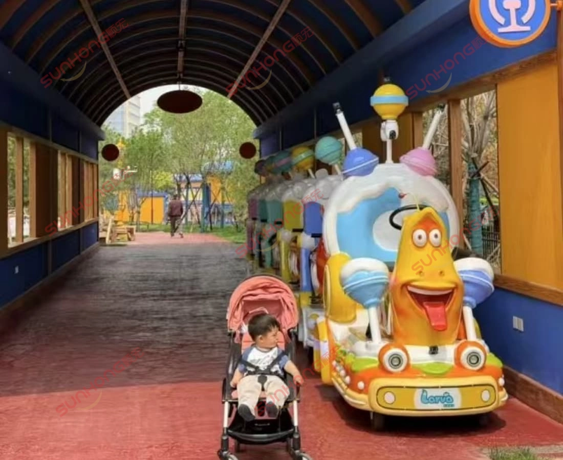 baby-posing-with-yellow-larva-train-head - SUNHONG Adorable baby takes a photo with the Yellow character of the Larva Ranger trackless train — a charming kids' ride available for sale. - SUNHONG