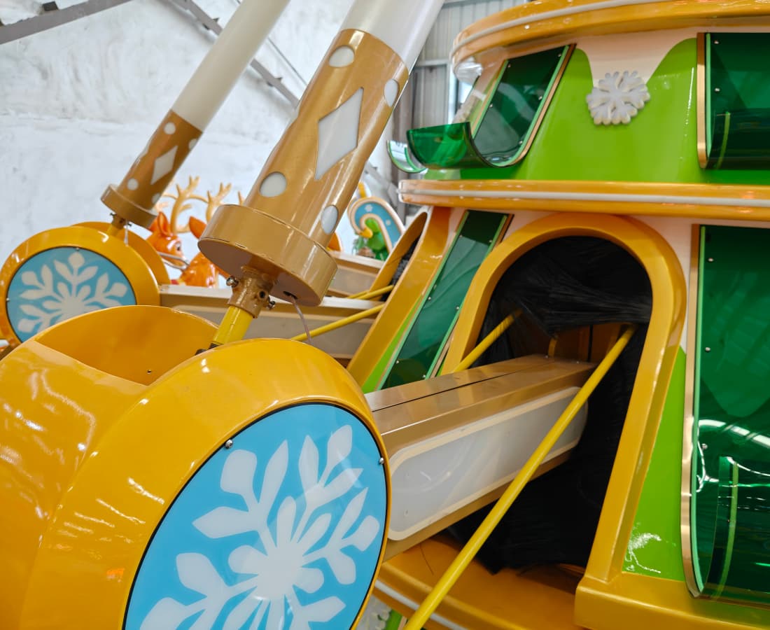 Close-up of a green and yellow carnival ride decorated with snowflake patterns. - SUNHONG