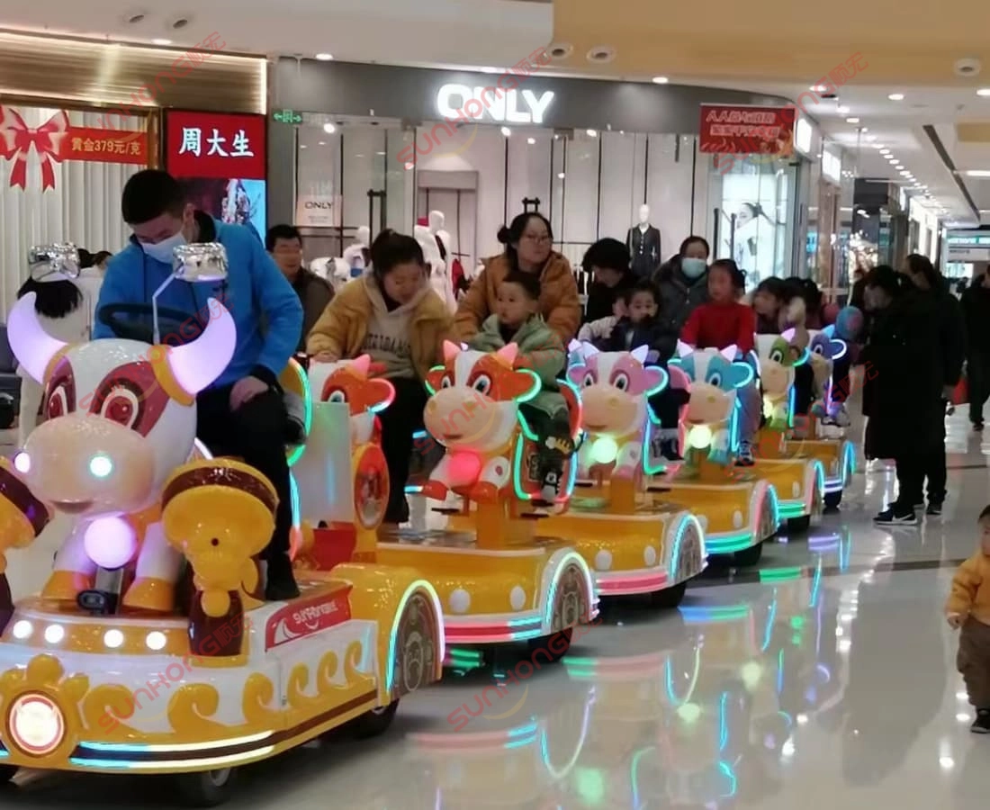 bull-train-riding-in-mall-electric-mini-train - SUNHONG Children enjoying bull-shaped mini train ride in shopping mall, small trains for parks - SUNHONG