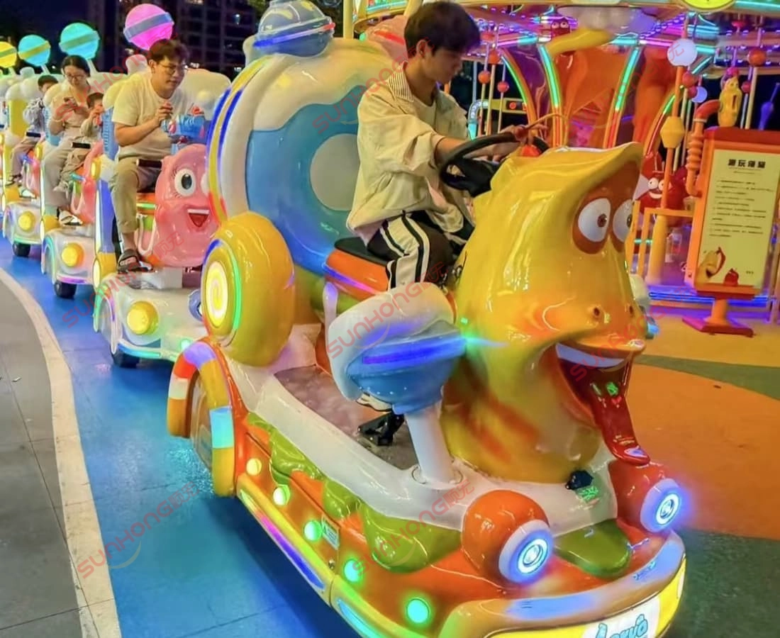 captain-yellow-driving-larva-train-at-dusk - SUNHONG At dusk in the Larva theme park, the captain rides Yellow with kids onboard — magical trackless train ride for sale. - SUNHONG