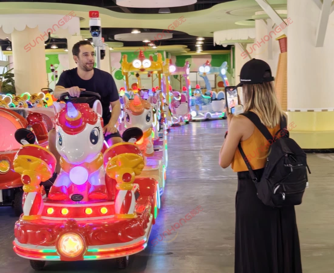 berwarna-warni-unicorn-naik-kereta-pengalaman-dalam-dalam - SUNHONG Lelaki memandu kereta api unicorn kiddie semasa dirakam di taman hiburan dalaman yang terang benderang. - SUNHONG