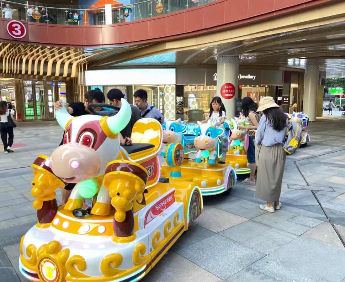 أشخاص يركبون قطارًا ملونًا على شكل بقرة من شركة SUNHONG، وهو قطار ترفيهي بدون مسار مصمم خصيصًا لمدن الملاهي وأماكن الترفيه العائلي - SUNHONG