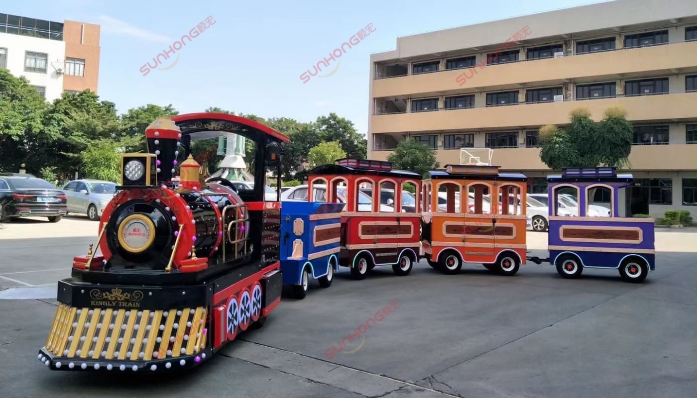 kingly-train-sunhong-factory Kingly Trackless Train displayed outside SUNHONG factory, showcasing colorful carriages and classic steam design – building a trackless train example