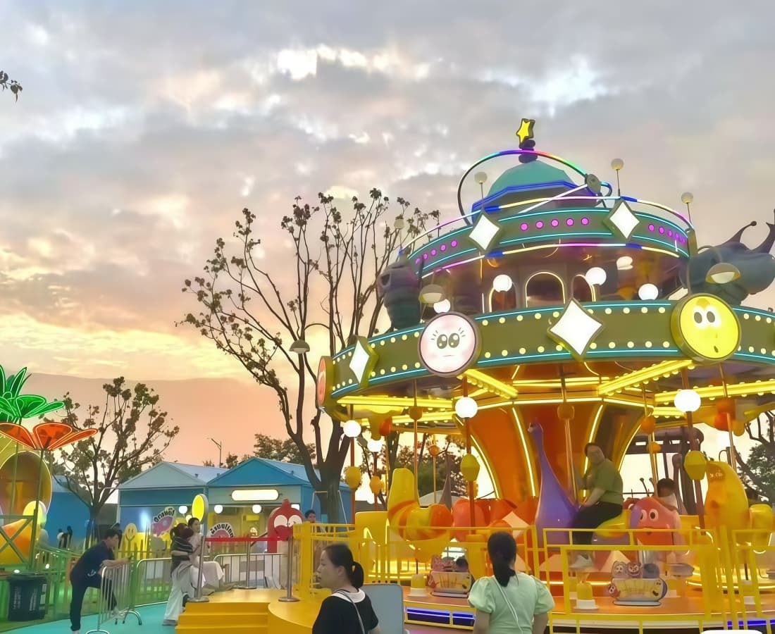 Passeio colorido &quot;Carrossel de Larvas&quot; em um parque com pessoas e o pôr do sol. - SUNHONG