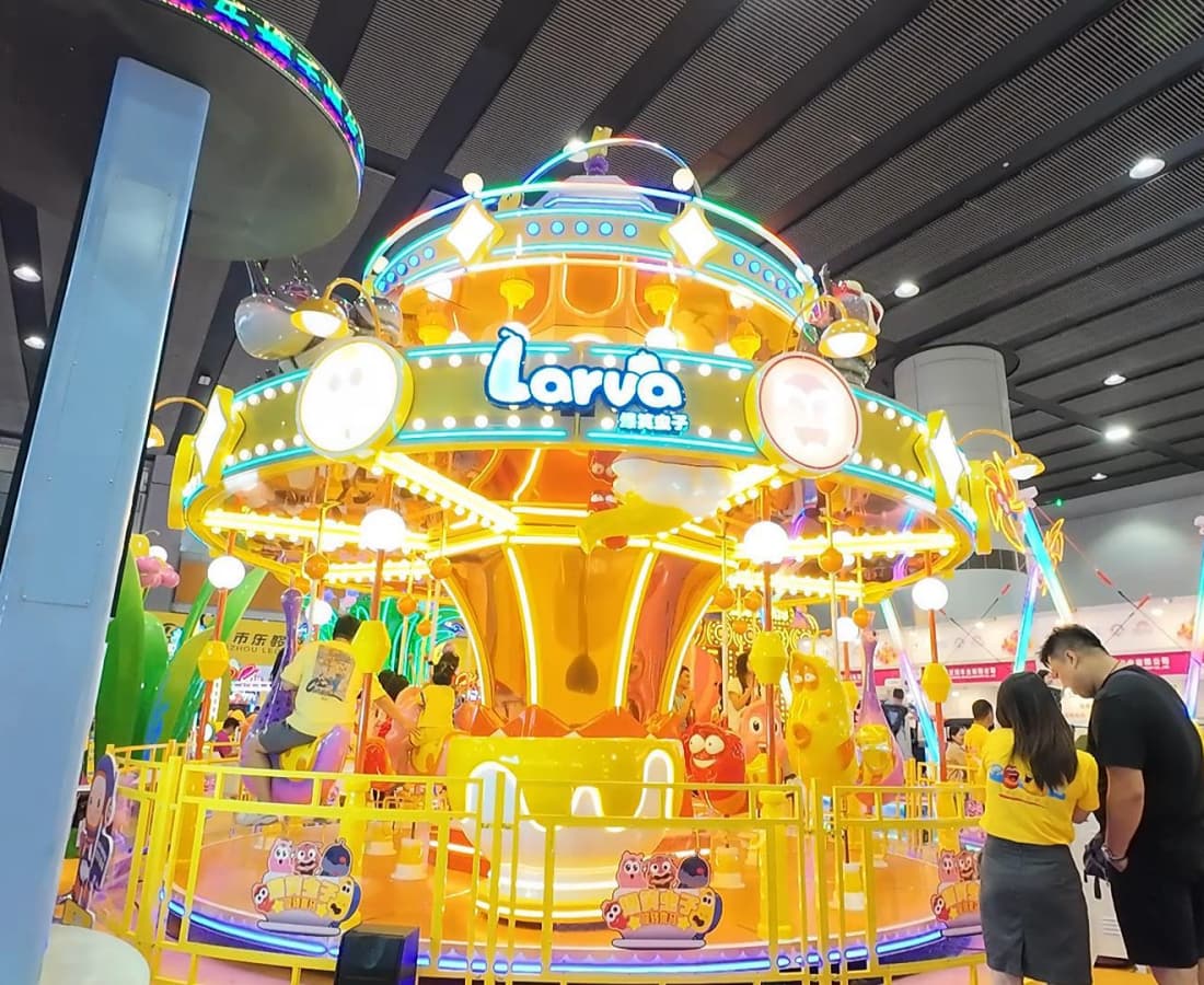 Carrossel de larvas coloridas na exposição SUNHONG com pessoas andando. - SUNHONG