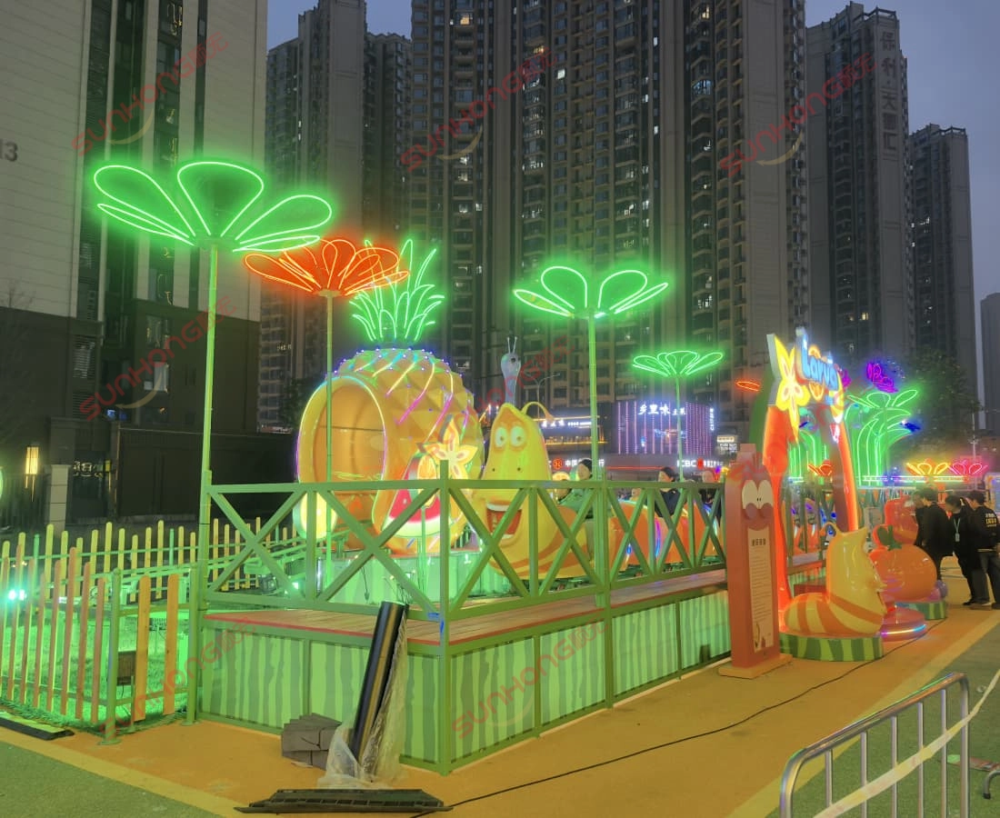 larva-fruitland-mini-coaster-evening-light-show - SUNHONG Evening view of Larva Fruitland mini coaster with glowing lights and vibrant ambiance. - SUNHONG
