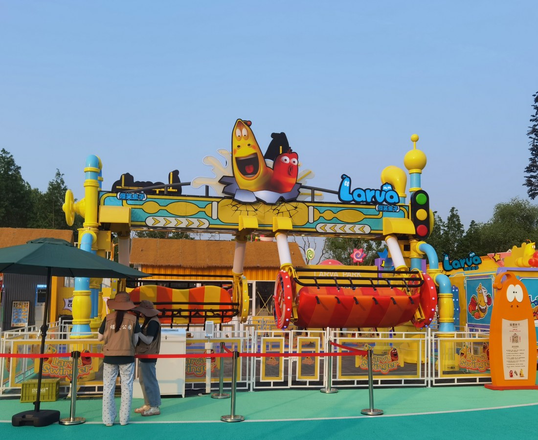 Larva Swing ride being tested at SUNHONG’s Larva-themed park, with two staff members in front. - SUNHONG