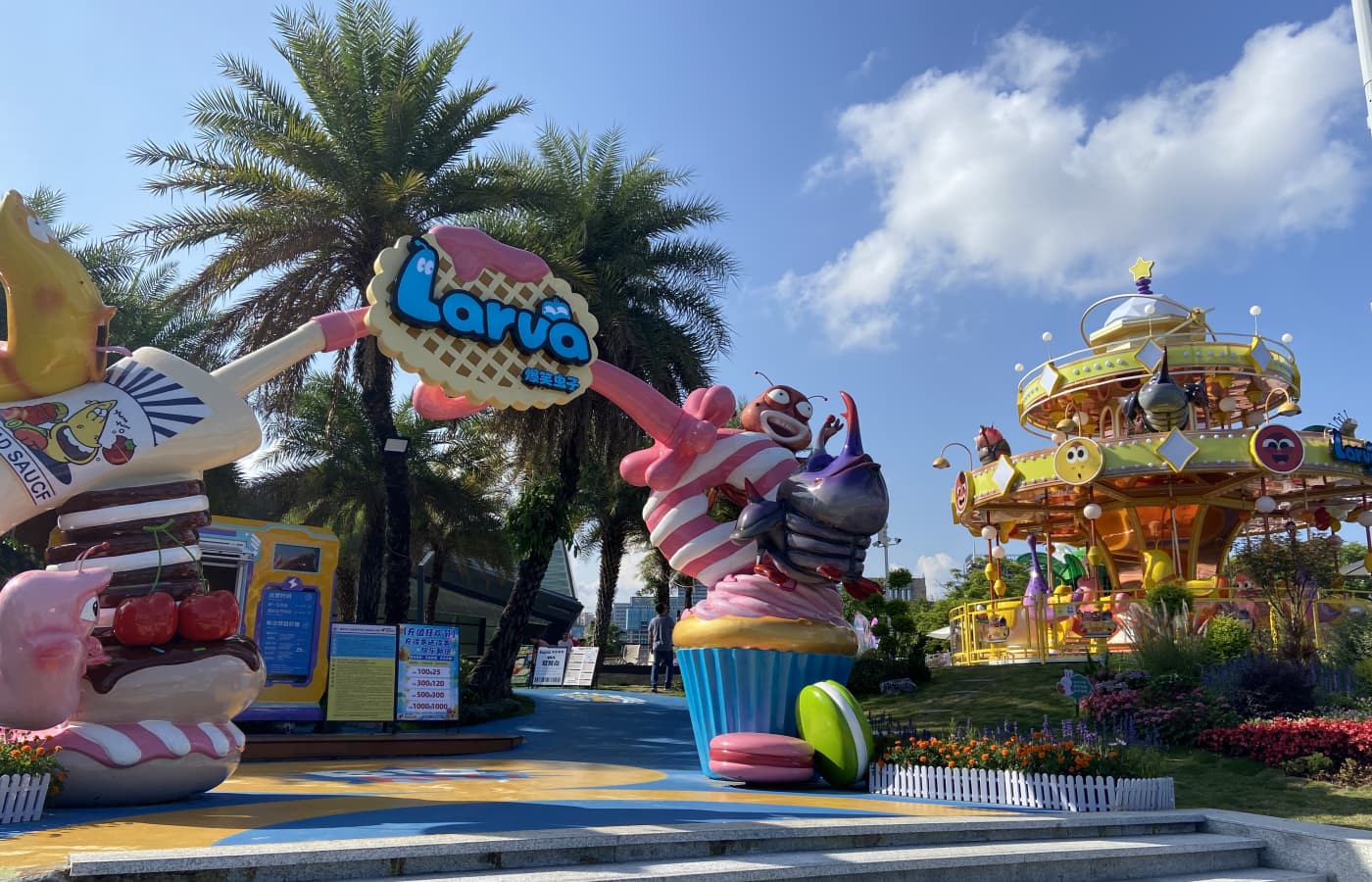 Entrance gate and Larva-themed carousel ride at an amusement park, featuring cartoon characters, candy decorations, and colorful design. - SUNHONG