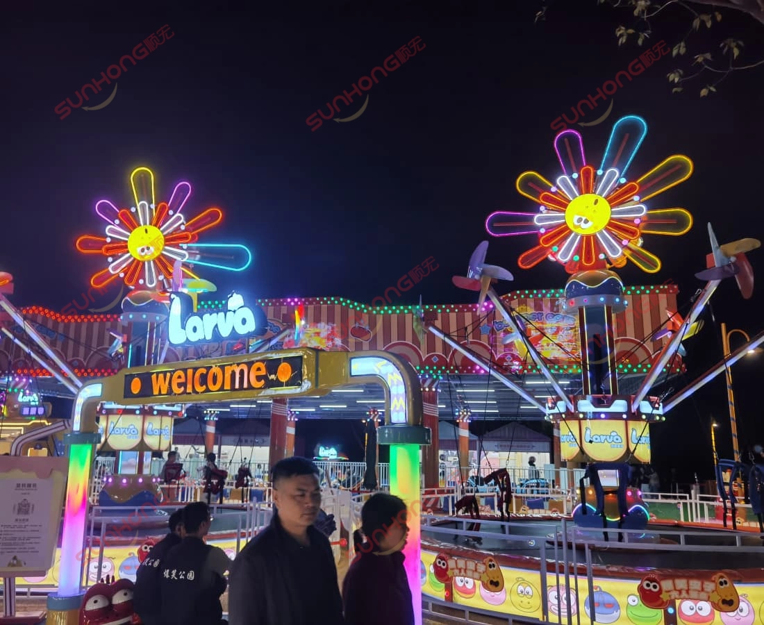 larva-windmill-trampoline-night-crowd-lights - SUNHONG Larva Windmill Trampoline glowing at night with flashing lights, attracting many children in the Larva park. - SUNHONG