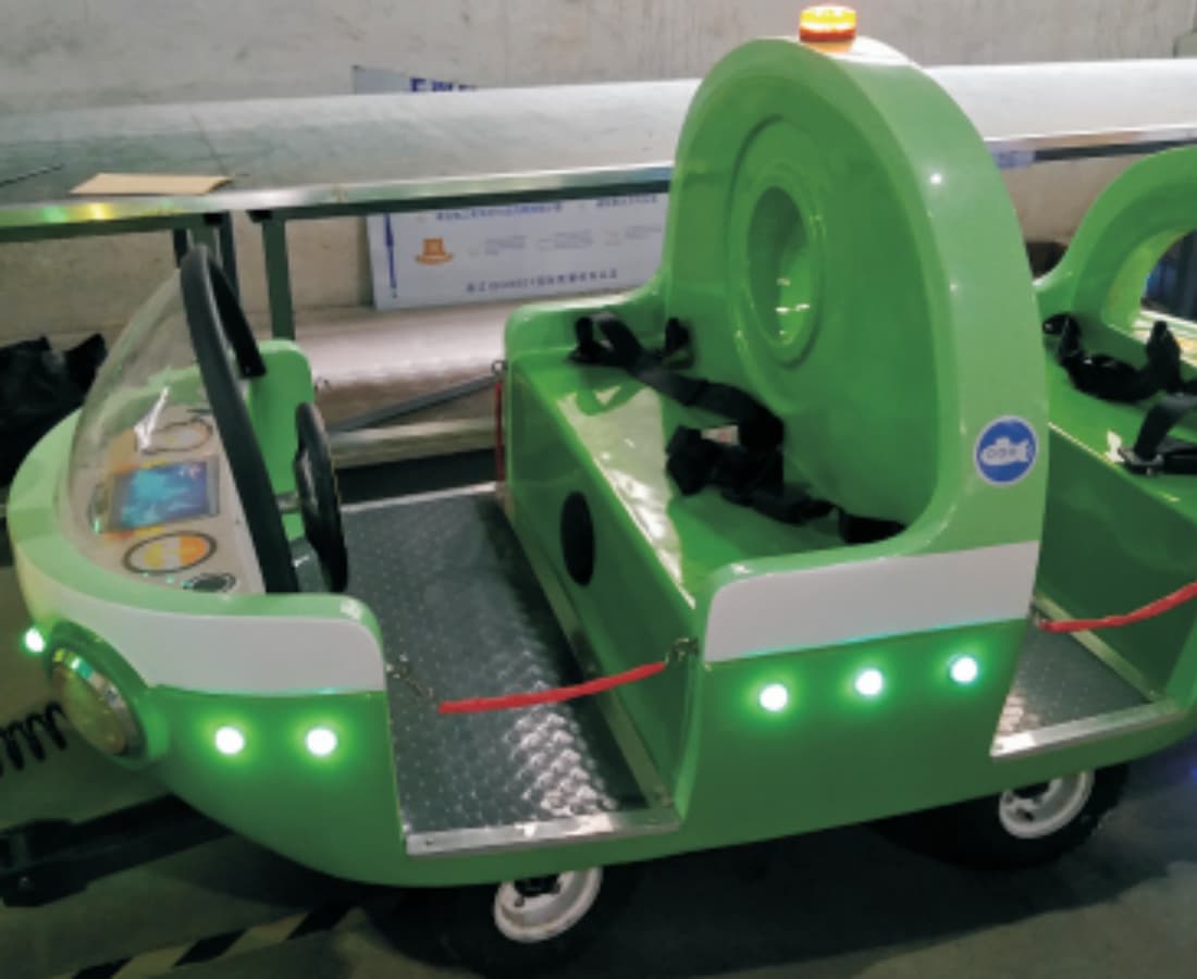 Interior de um vagão verde com assentos duplos e cintos de segurança no trem elétrico sem trilhos Ocean Train - SUNHONG