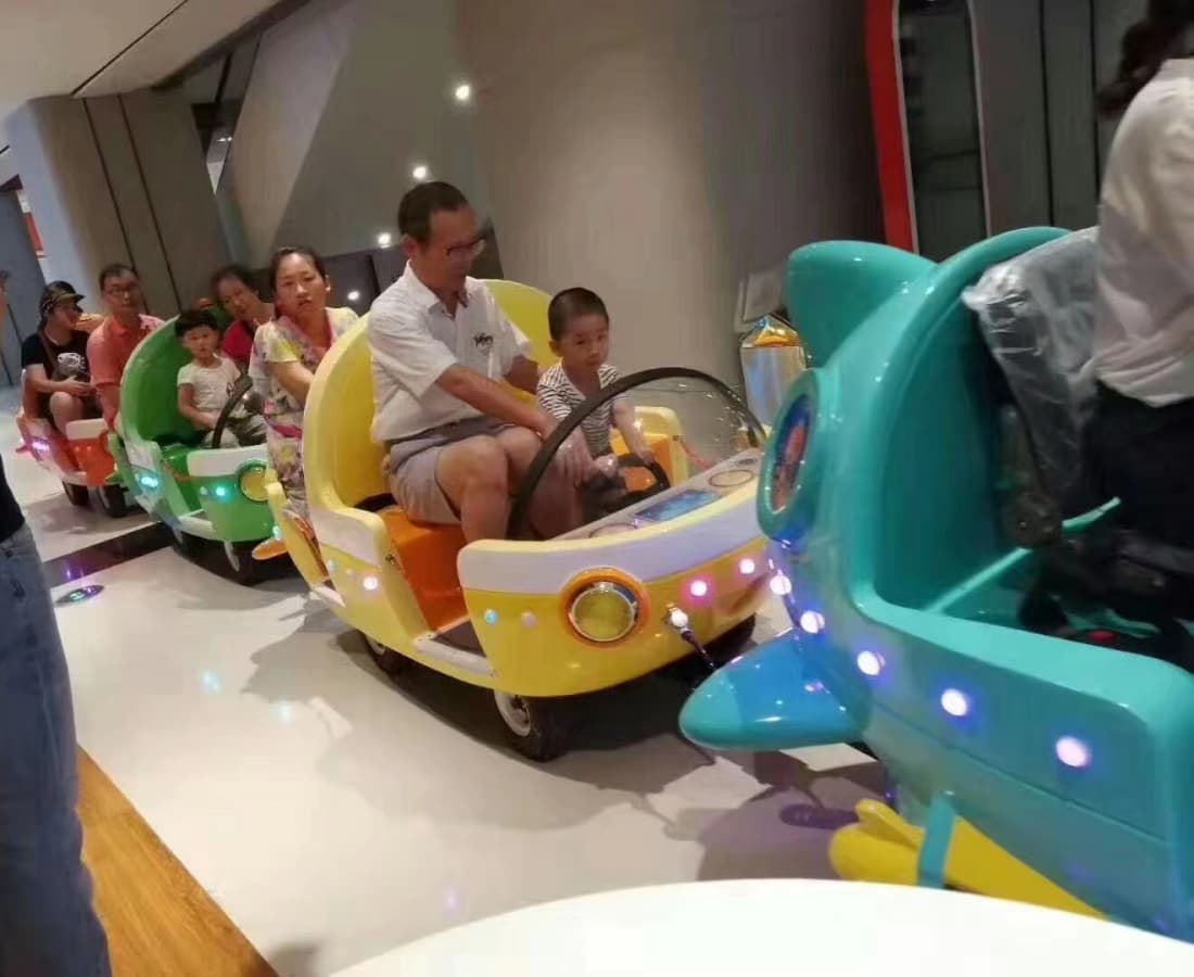 Pais e filhos aproveitam um passeio de trem elétrico colorido com tema oceânico em um complexo fechado. - SUNHONG