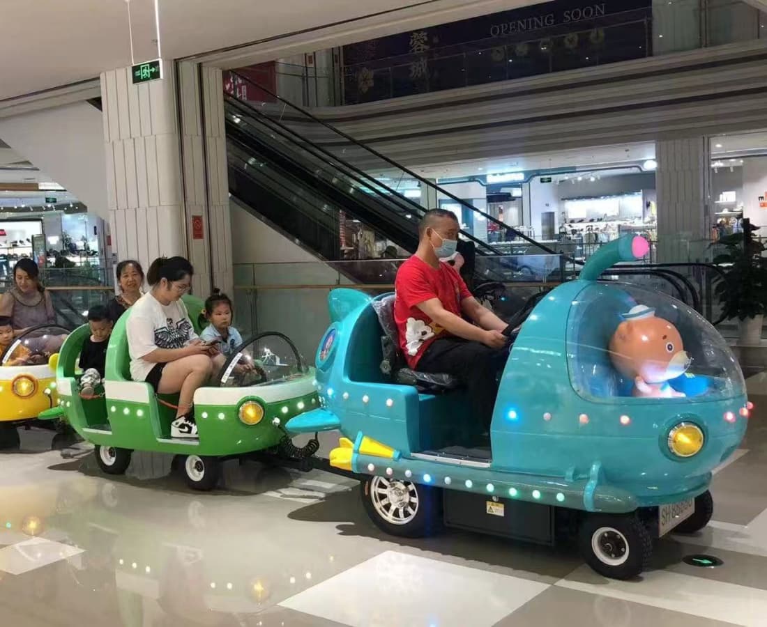 Famílias andando em um trem elétrico colorido sem trilhos dentro de um shopping, ideal para o entretenimento das crianças. - SUNHONG