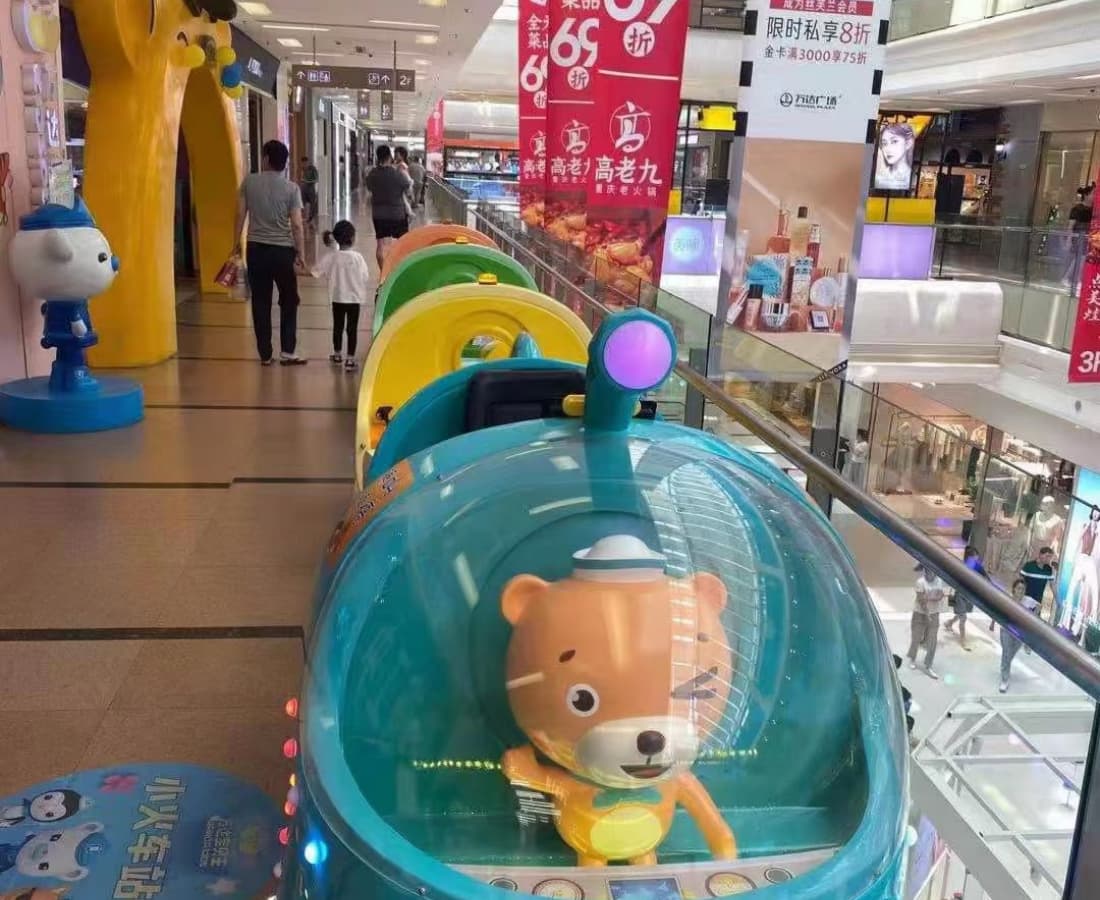 Trem elétrico sem trilhos com personagem de urso-do-mar operando no andar superior de um shopping comercial. - SUNHONG